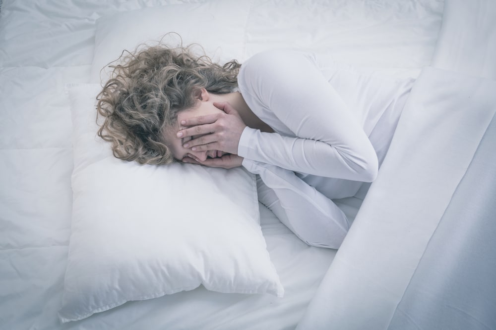 Tired woman laying in bed with sleeping disorder